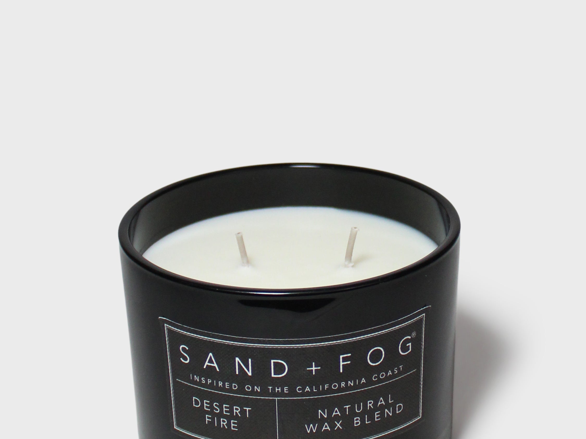 Black glass scented candle with Sand+Fog label, white wax and two wicks