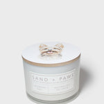 Sand + Paws scented candle in white glass jar with label and cream lid topper