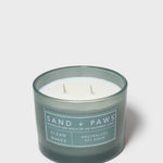 Scented candle in dark teal glass jar with "Sand + Paws" beach dog label