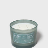 Scented candle in dark teal glass jar with "Sand + Paws" beach dog label
