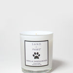 Scented candle in clear glass jar with Sand + Paws Vanilla Sandalwood label