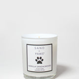 Scented candle in clear glass jar with Sand + Paws Vanilla Sandalwood label