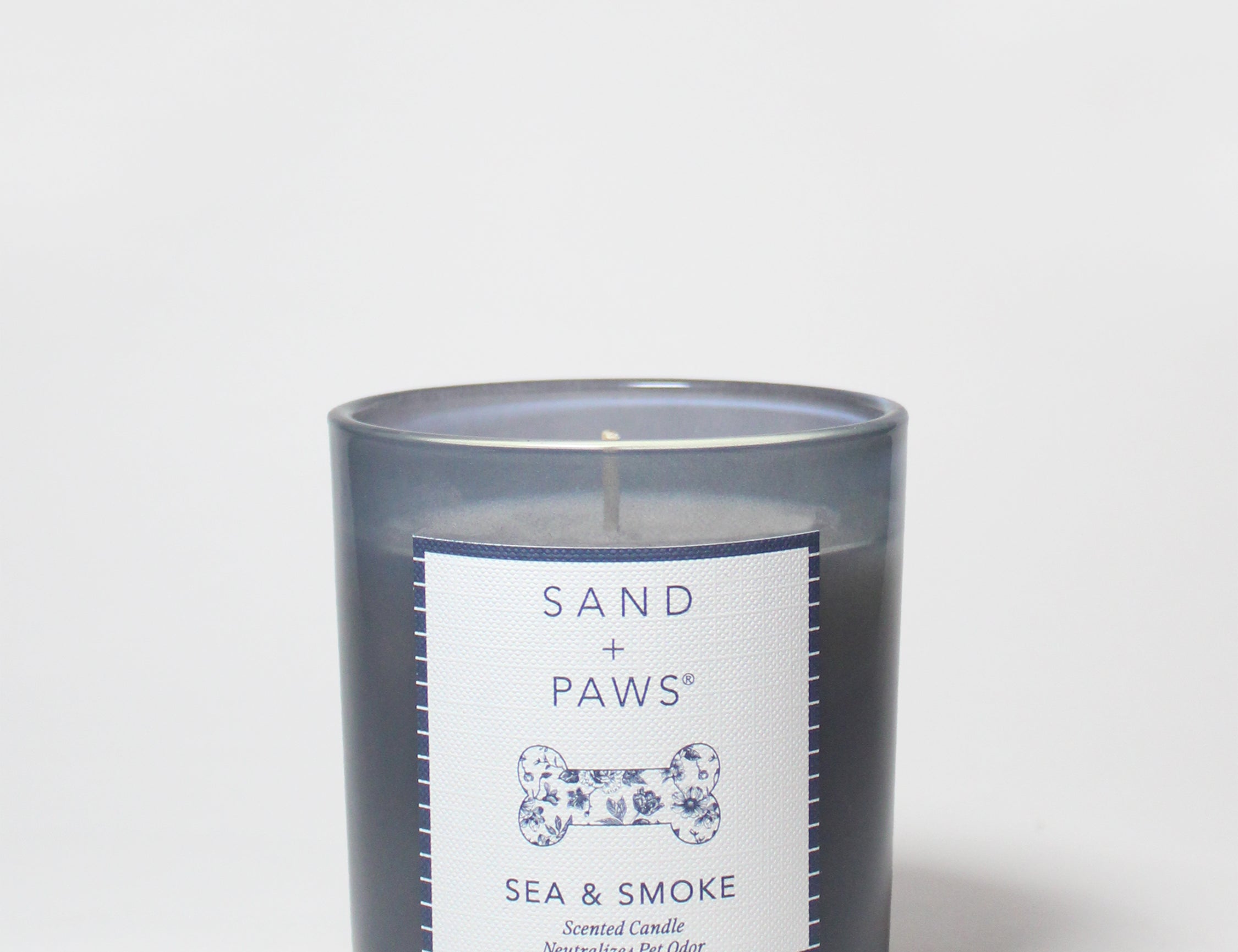 Sand + Paws scented candle in dark blue glass jar with Sea & Smoke label and visible wick
