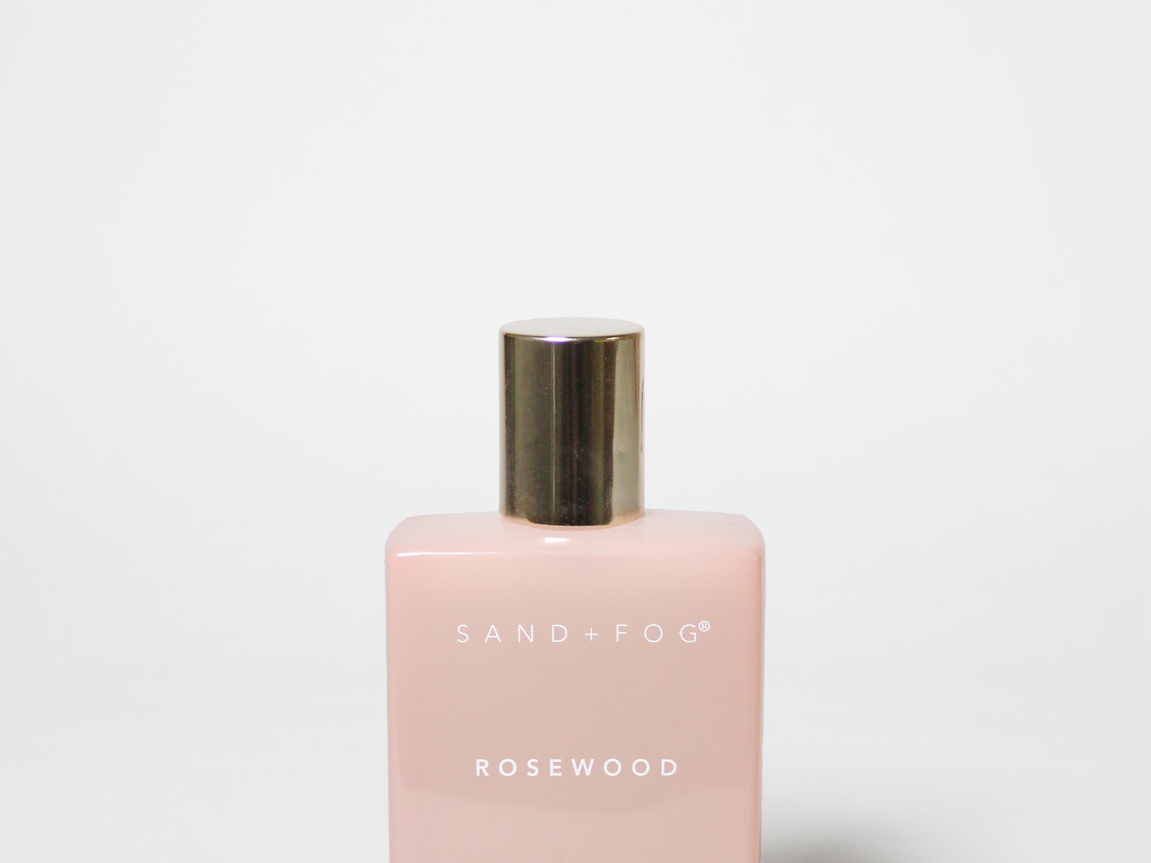 Pink perfume bottle with gold cap on a white background