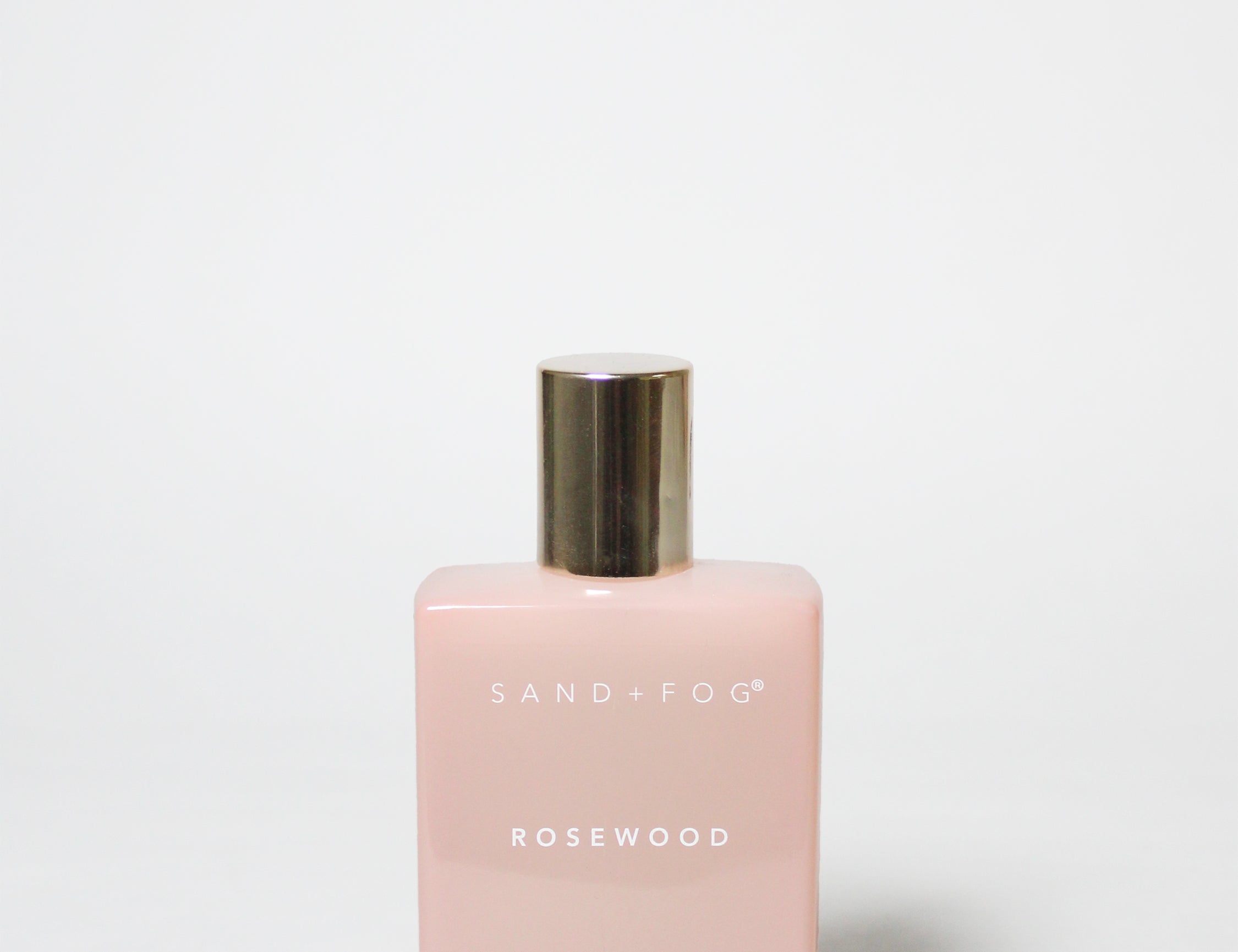 Pink perfume bottle with gold cap on a white background