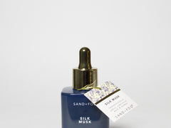 Perfume oil dropper bottle with gold cap, blue label, and card tag