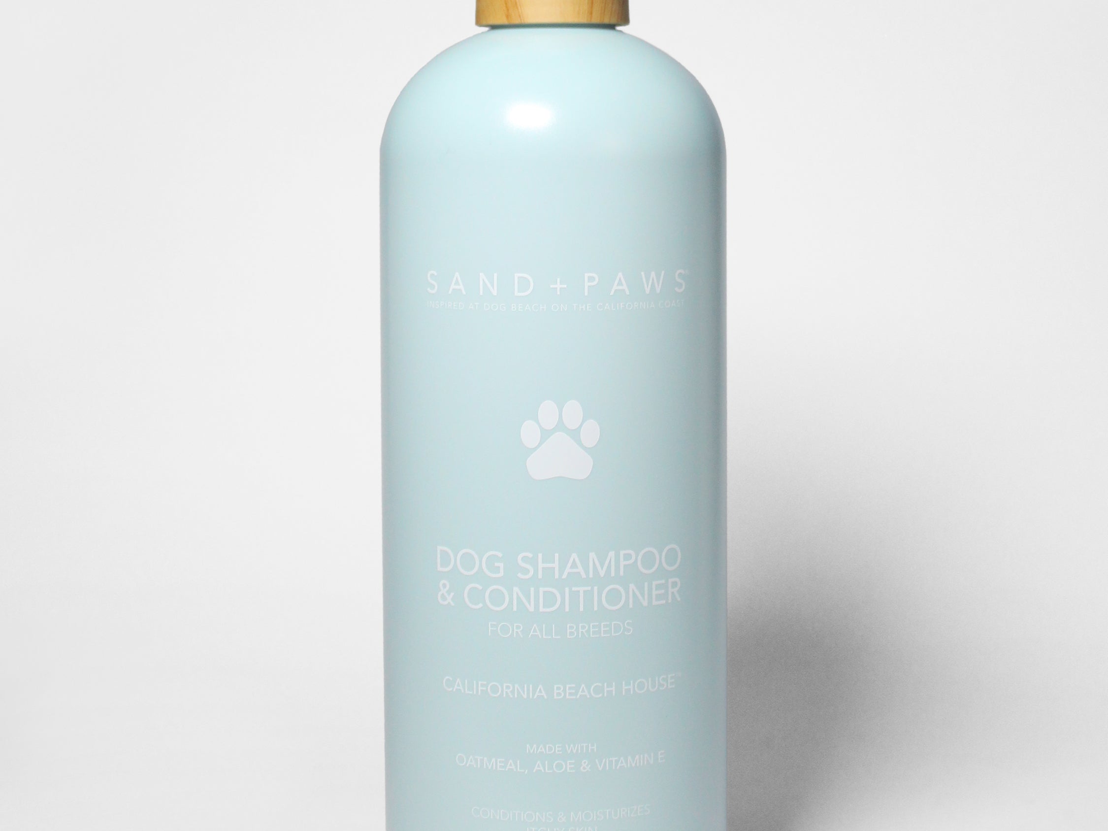 Sand + Paws dog shampoo and conditioner bottle, light blue with pump and paw logo