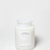 Scented candle in frosted white glass jar with printed label and white wax top