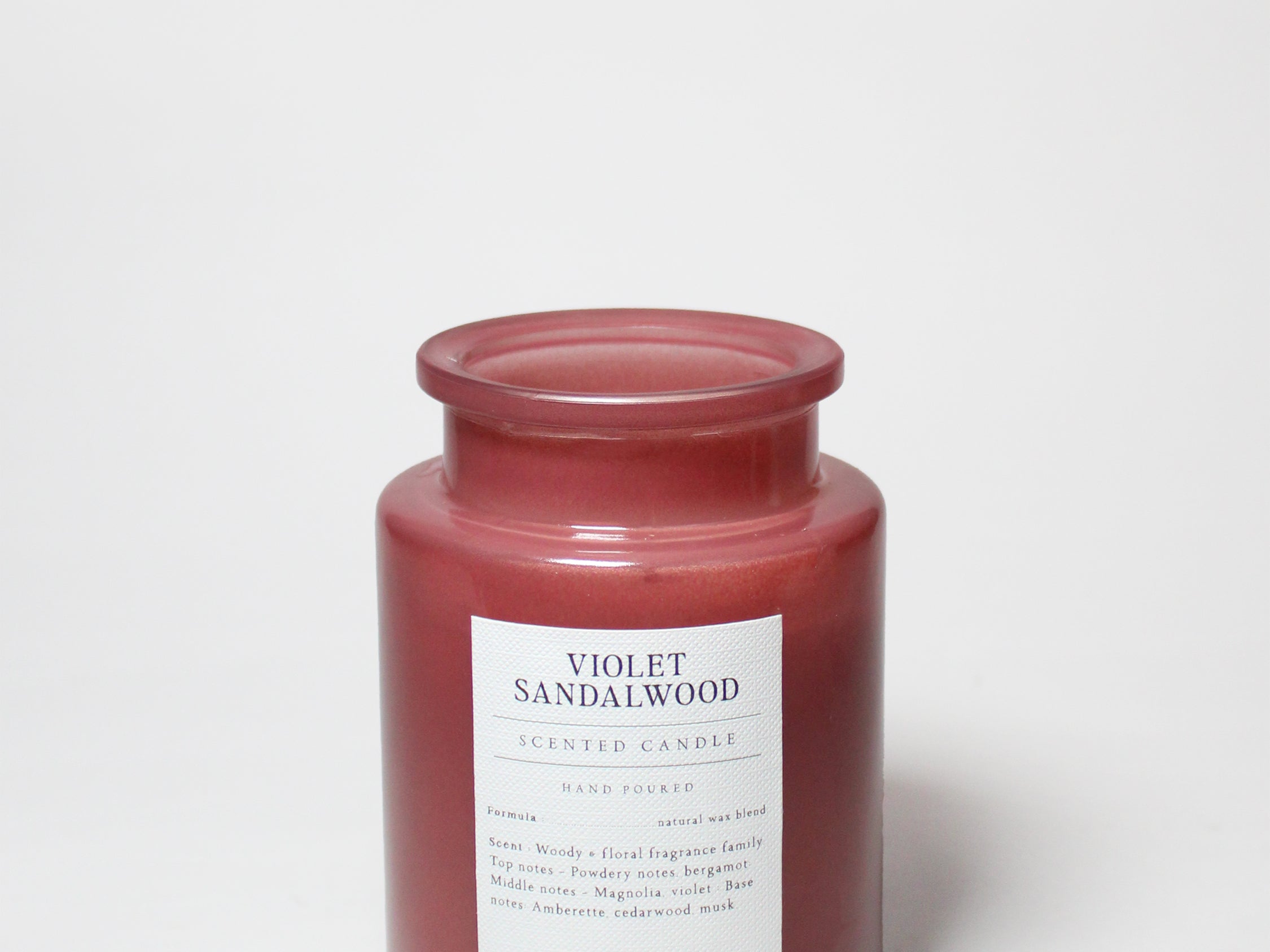 Maroon scented candle jar with Violet Sandalwood label; visible wax top.