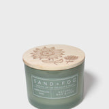 Green glass jar scented candle with botanical-printed cream lid, 12 oz