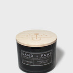 Sand + Paws teakwood scented candle with light wood lid on black glass jar