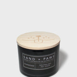 Sand + Paws teakwood scented candle with light wood lid on black glass jar