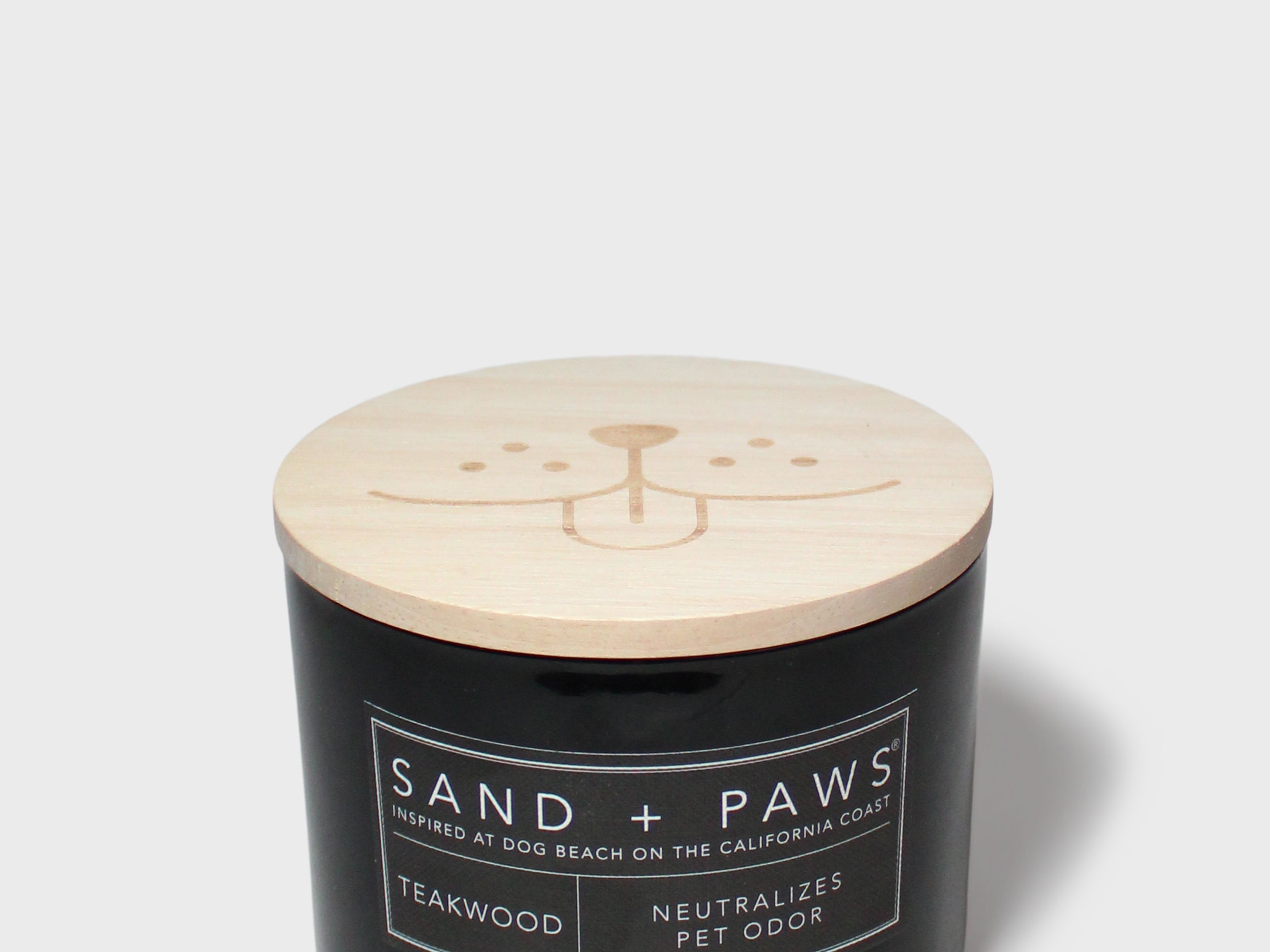 Sand + Paws teakwood scented candle with light wood lid on black glass jar