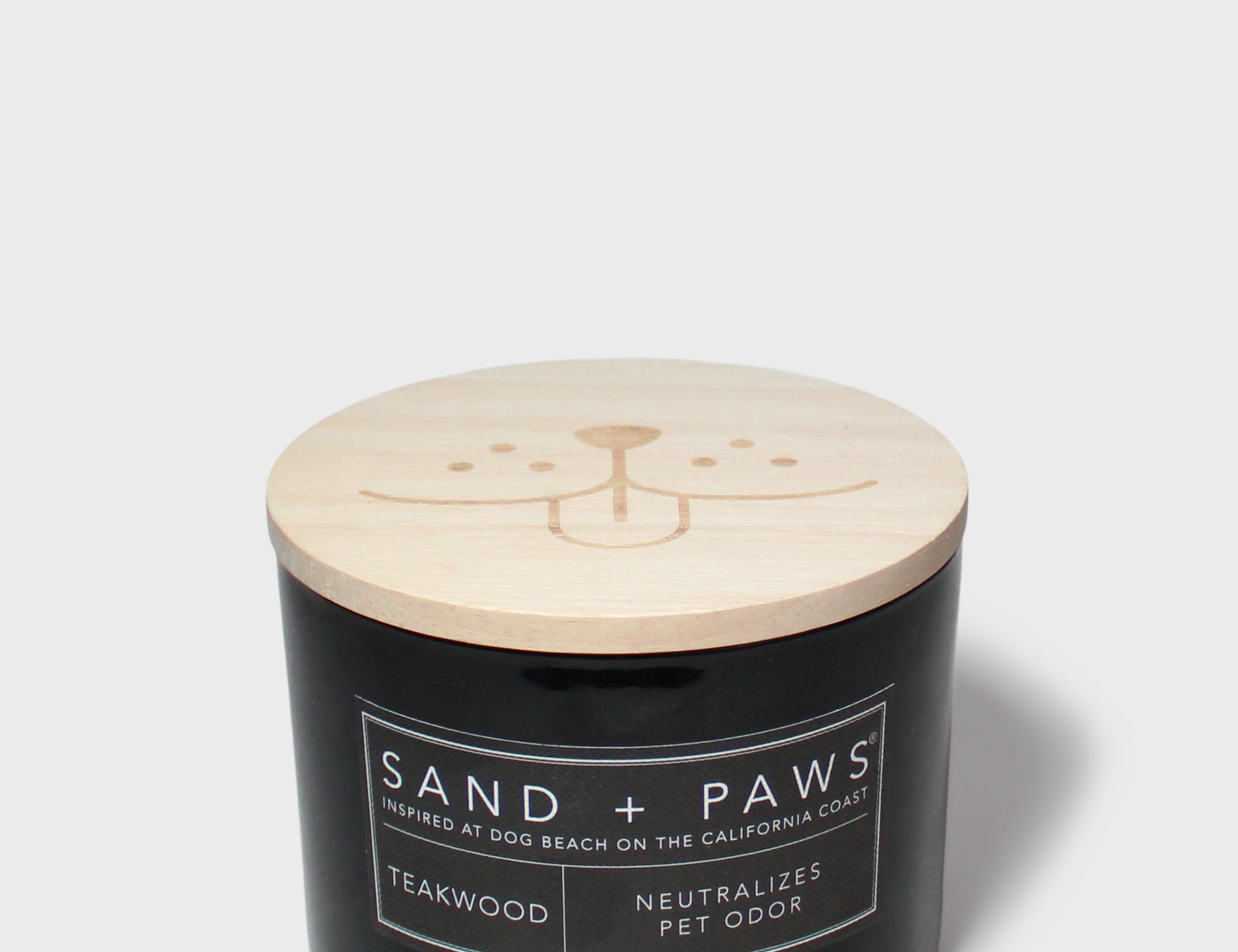 Sand + Paws teakwood scented candle with light wood lid on black glass jar