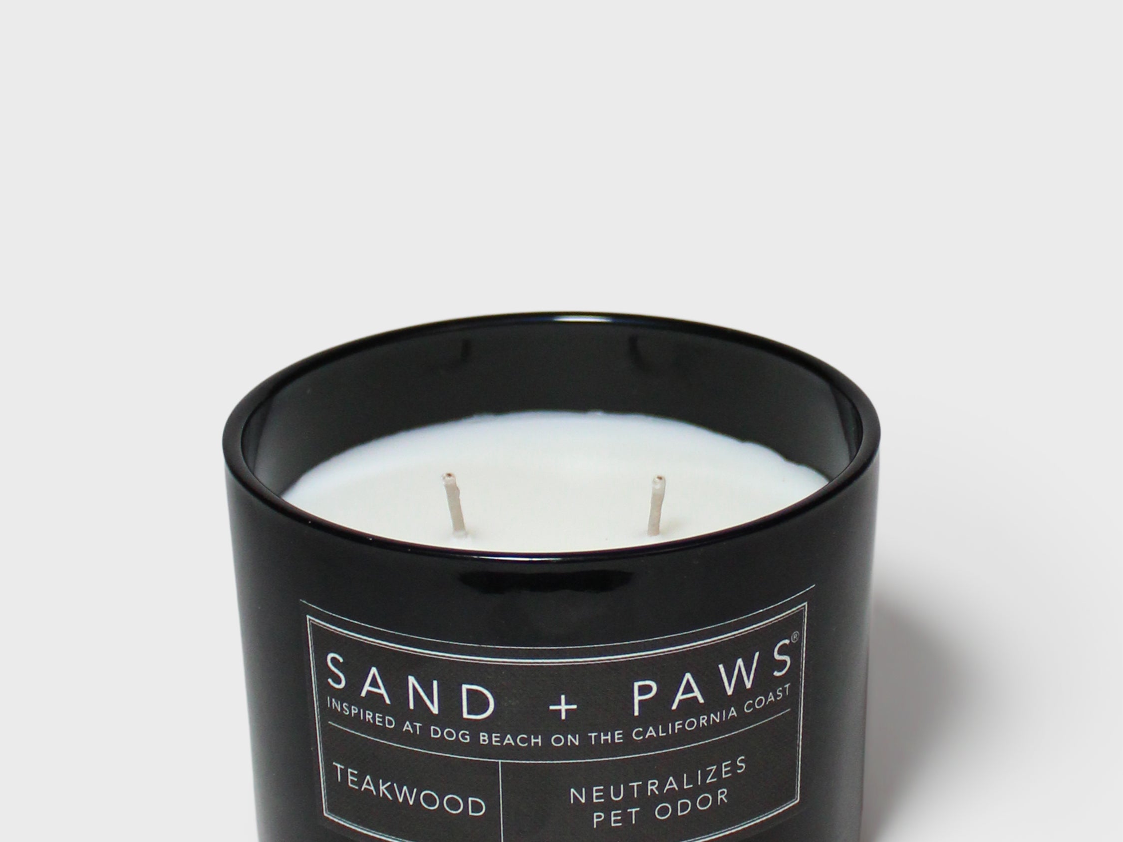 Sand + Paws teakwood scented candle in black glass jar with white wax and wick