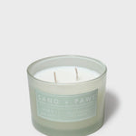 Sage green scented candle in glass jar with two visible wicks and label