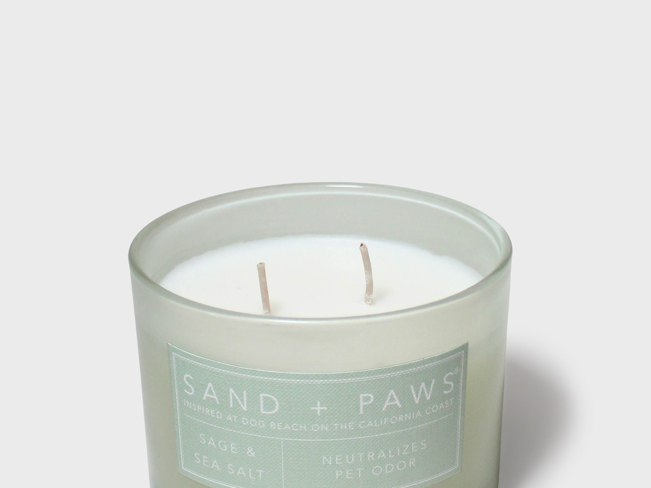 Sage green scented candle in glass jar with two visible wicks and label