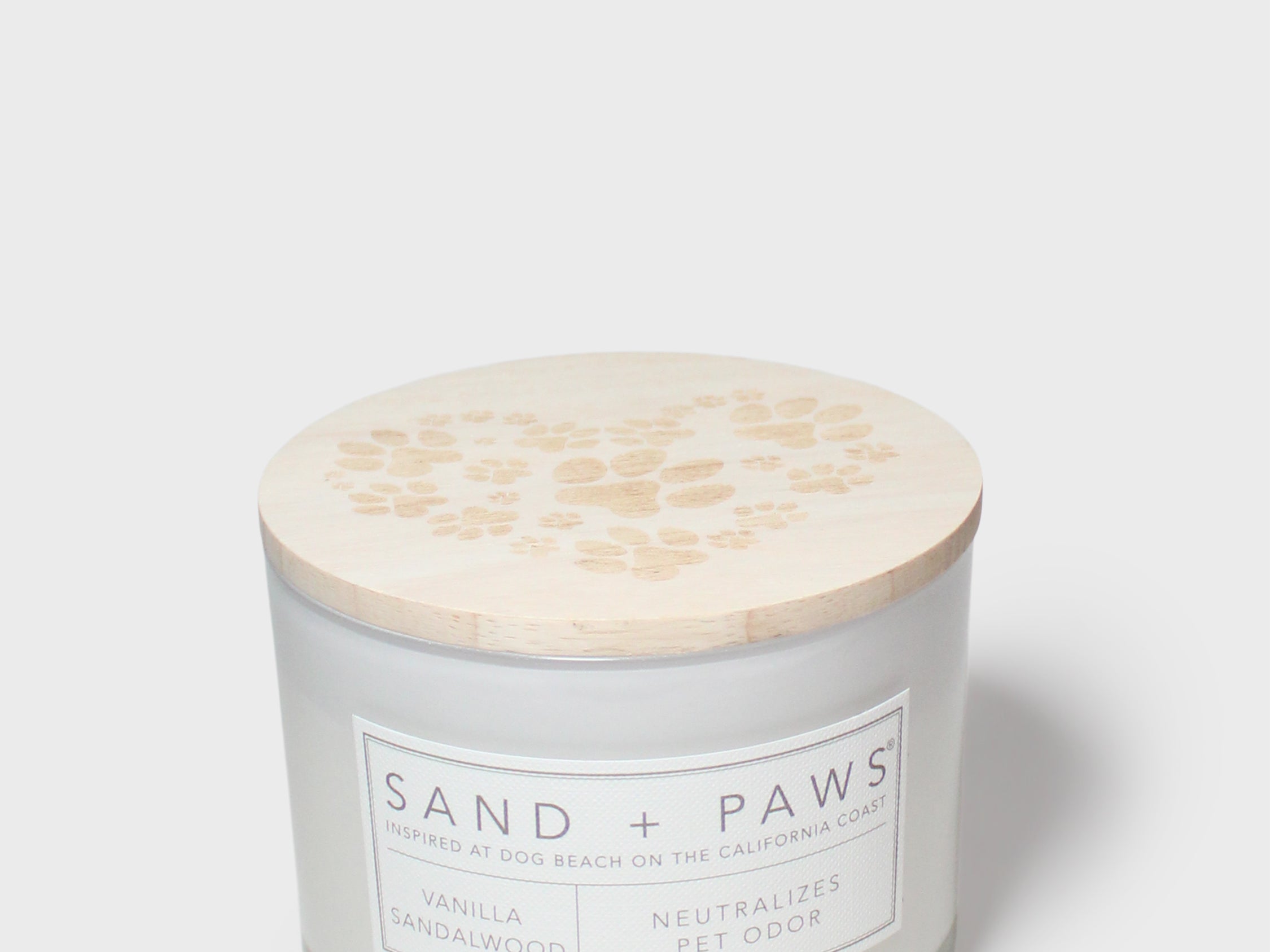 Scented candle with beige paw-print lid and Sand + Paws label