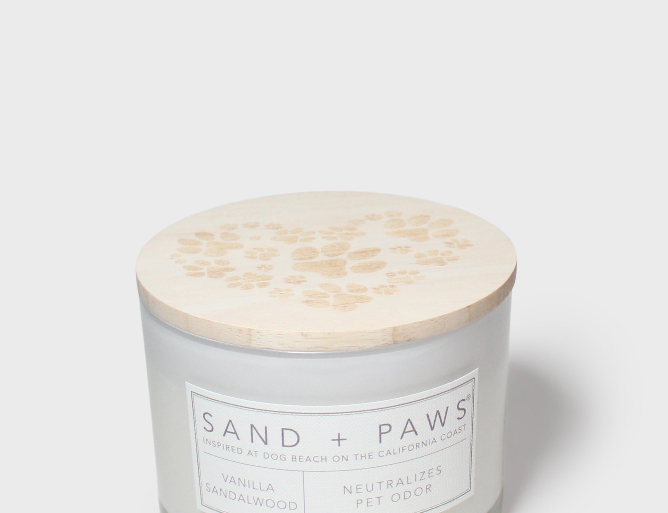 Scented candle with beige paw-print lid and Sand + Paws label