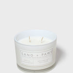 White scented candle jar with Sand + Paws label and two wicks