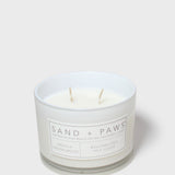 White scented candle jar with Sand + Paws label and two wicks