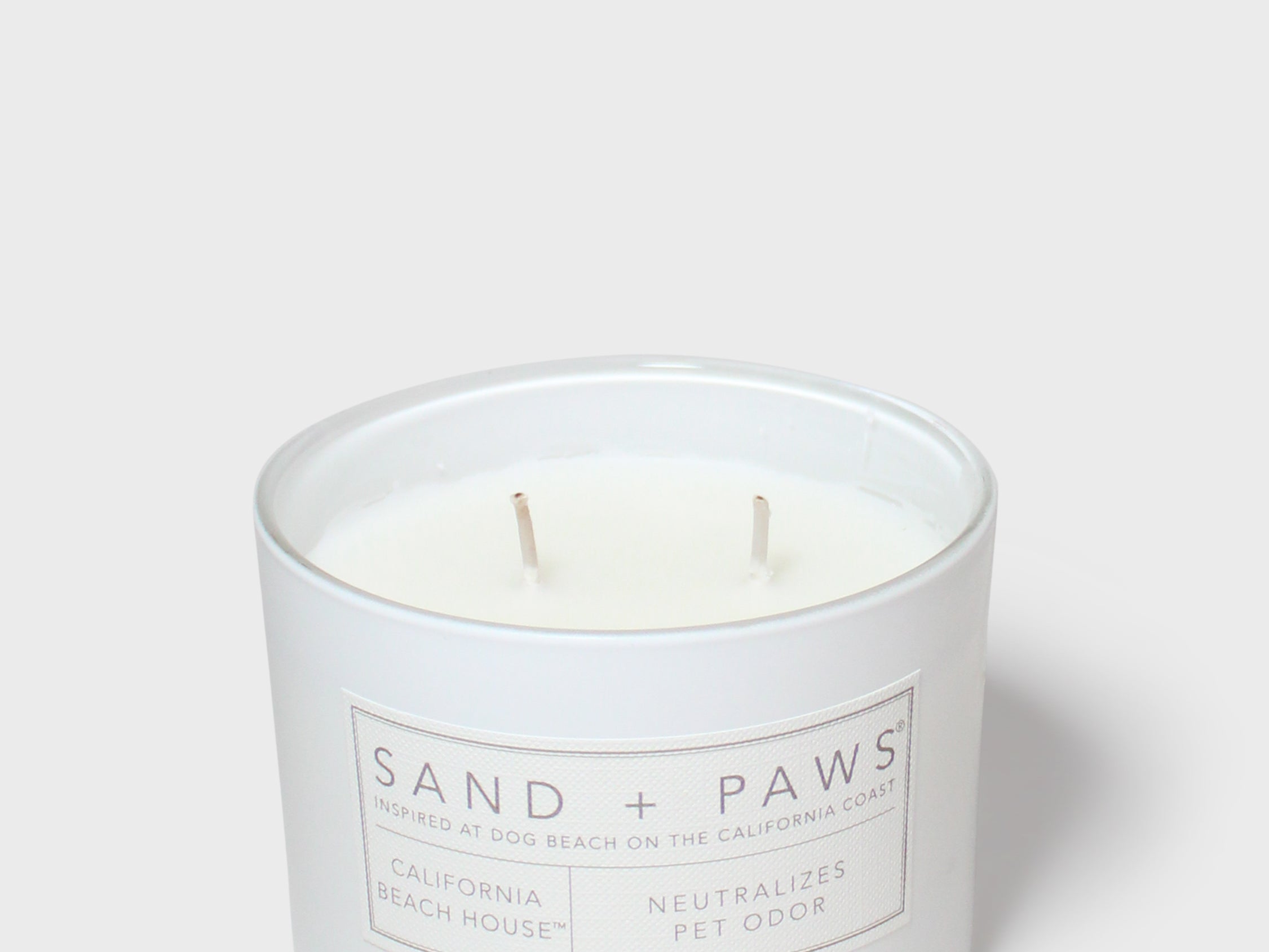 Sand + Paws scented candle in white glass jar with two wicks