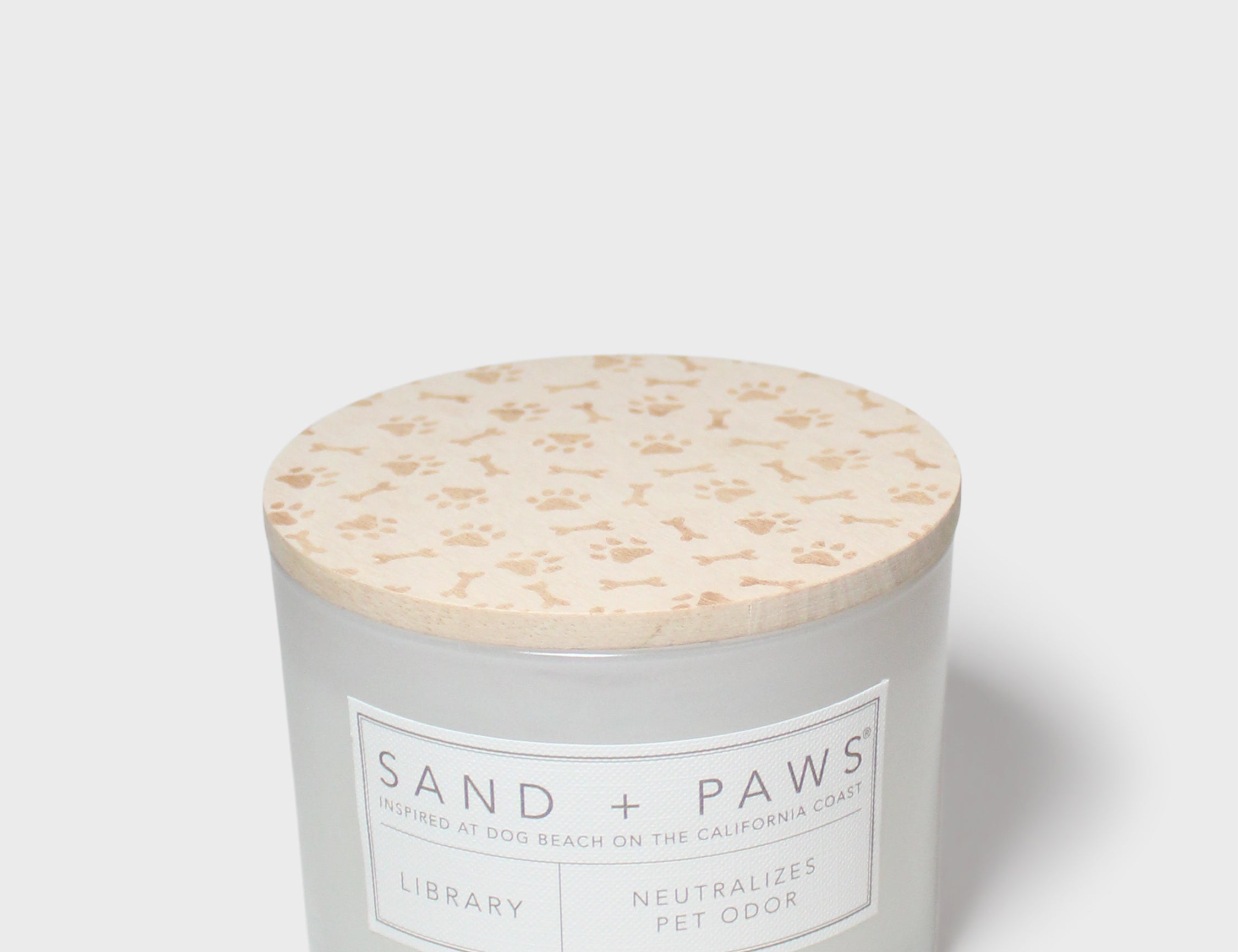 12 oz scented candle with Sand + Paws label and cream patterned lid top