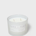 12 oz scented candle jar, Sand + Paws label, two wooden wicks visible