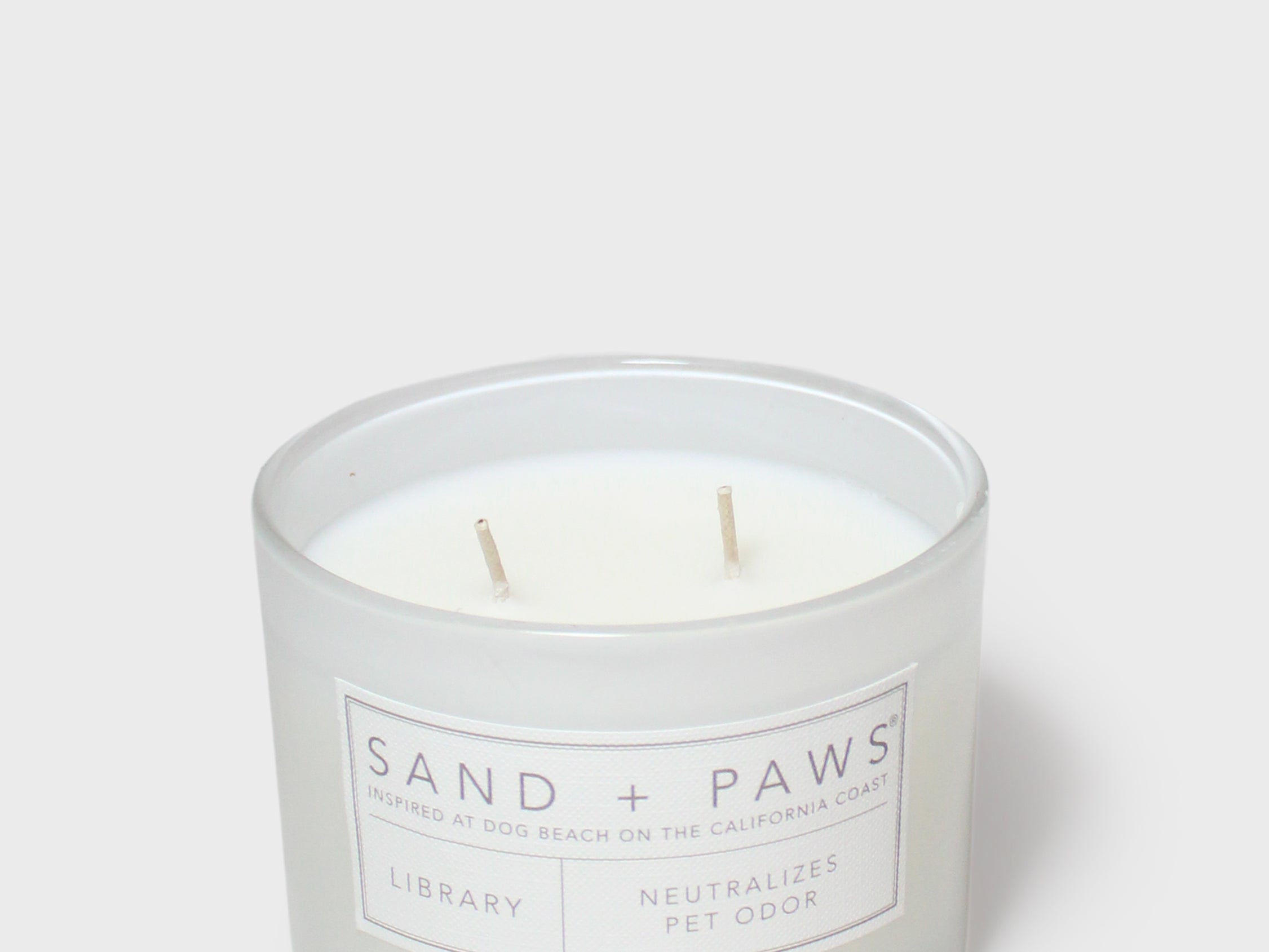 12 oz scented candle jar, Sand + Paws label, two wooden wicks visible