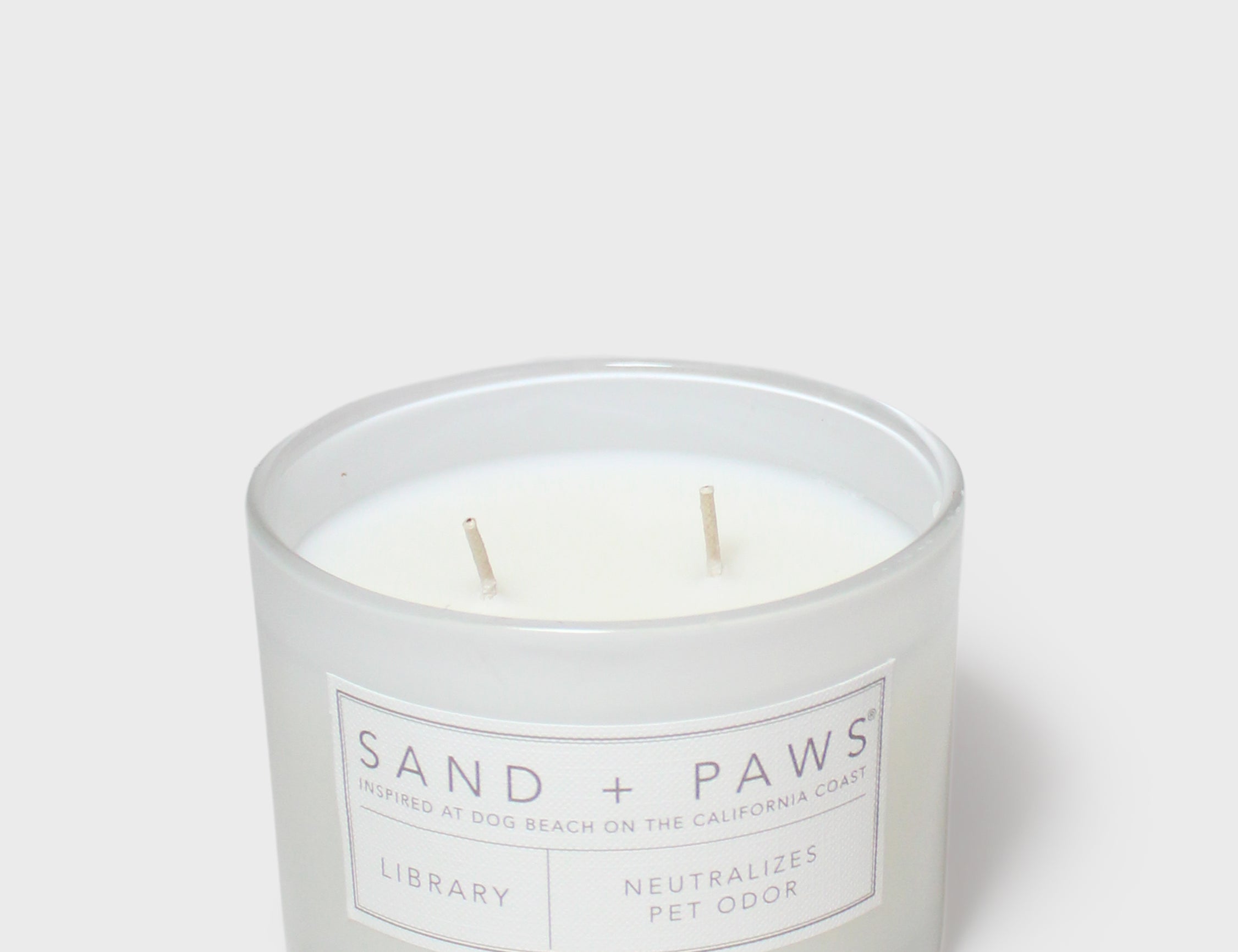 12 oz scented candle jar, Sand + Paws label, two wooden wicks visible