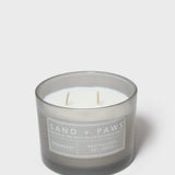 Gray glass jar scented candle with white wick and 'Sand + Paws' Speakeasy label