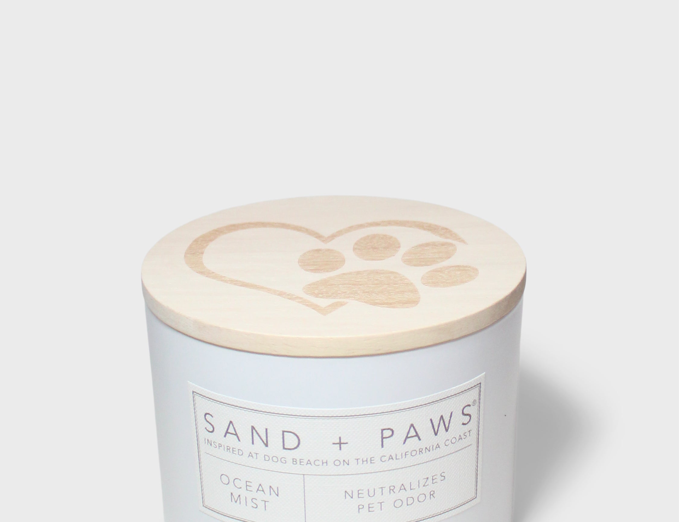 Sand + Paws scented candle with lid showing paw-print heart icon