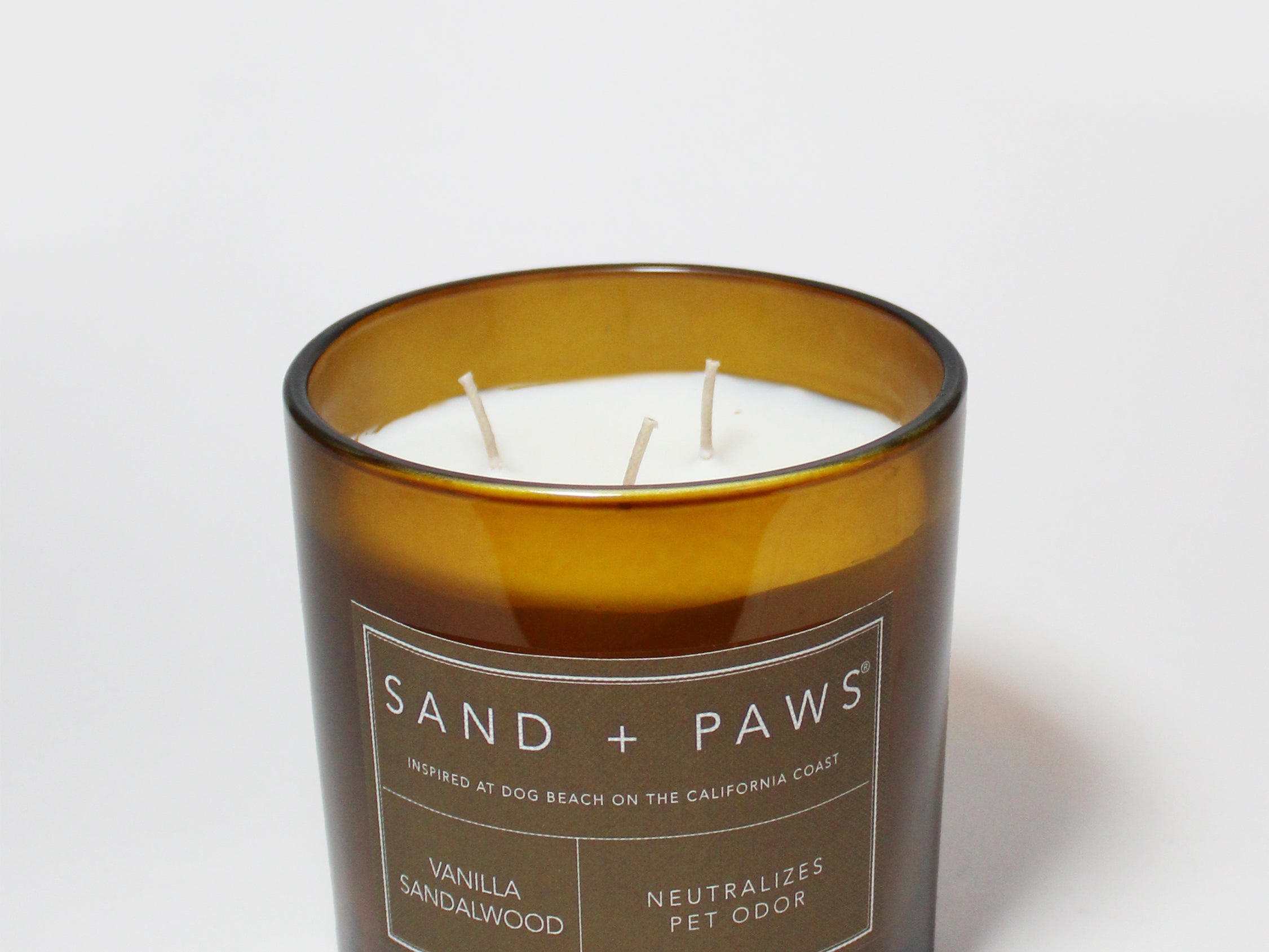 Sand + Paws scented candle in amber glass with label and three wicks