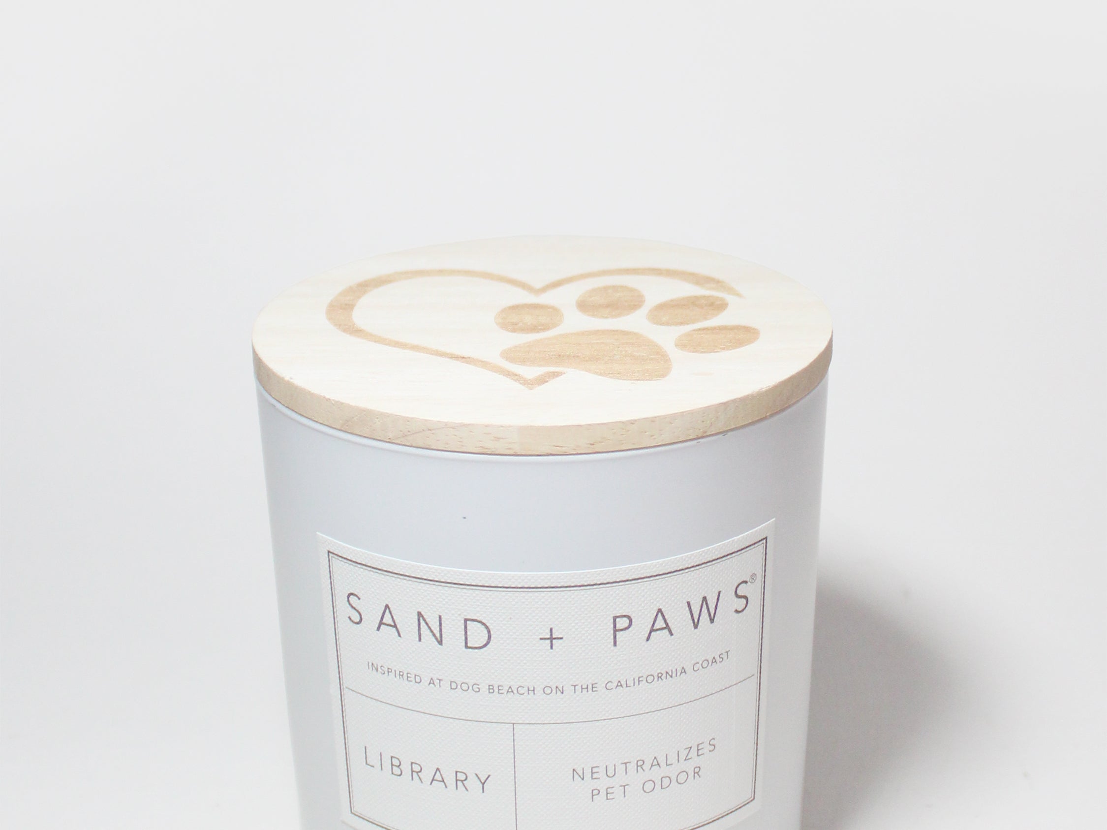 White candle jar with Sand + Paws Library label and lid paw-print top