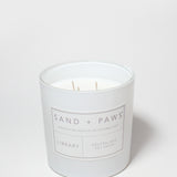 White candle jar with Sand + Paws Library label and neutralizes pet odor wording