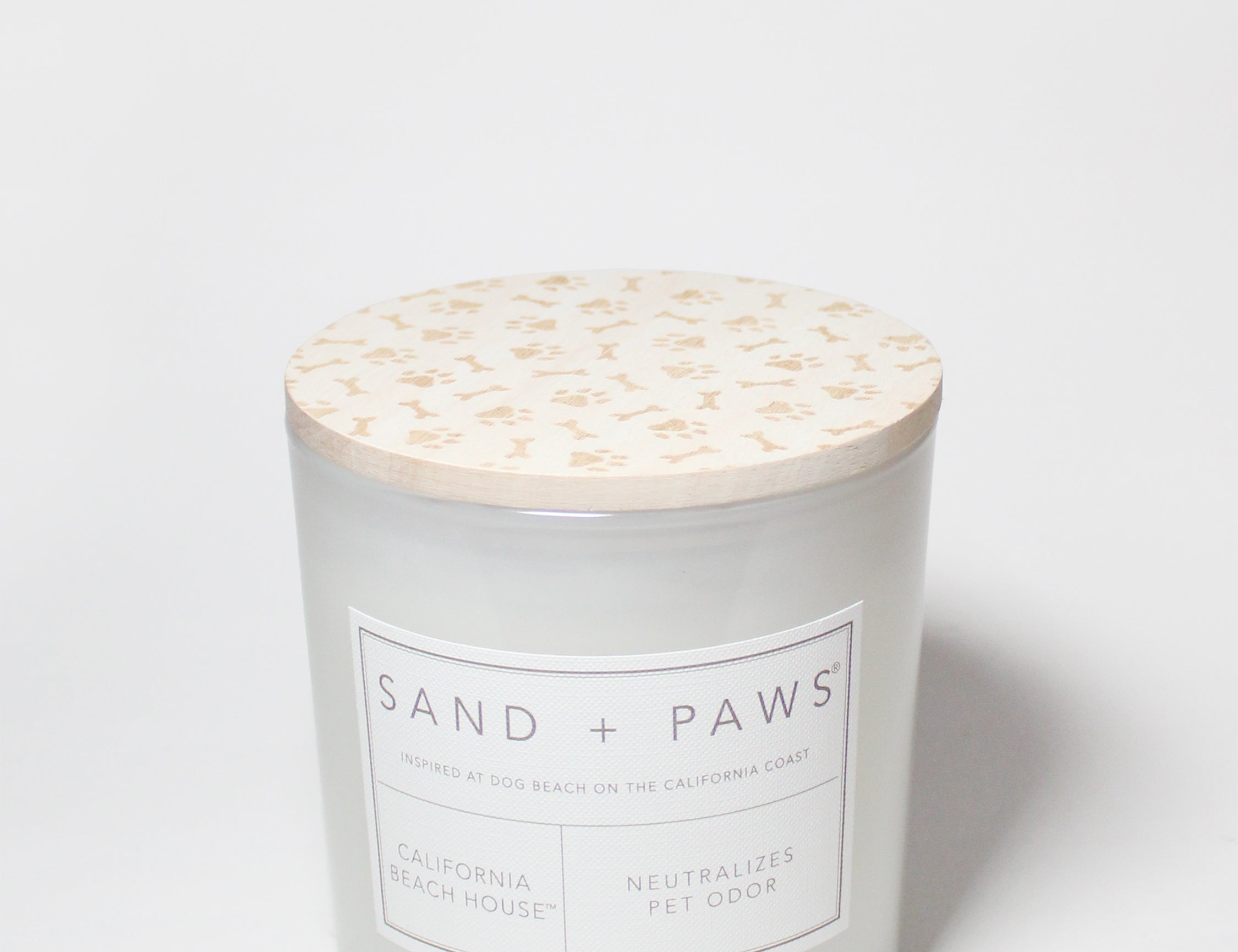 Sand + Paws scented candle jar with printed label and beige speckled lid