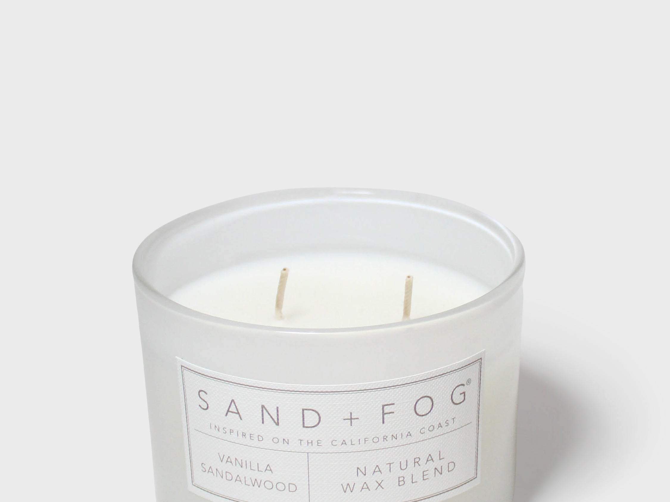 Sandalwood-vanilla scented candle in white glass jar with two wicks