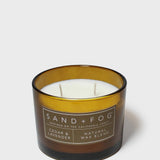 Cedar-scented candle in dark glass jar with amber band and two wicks