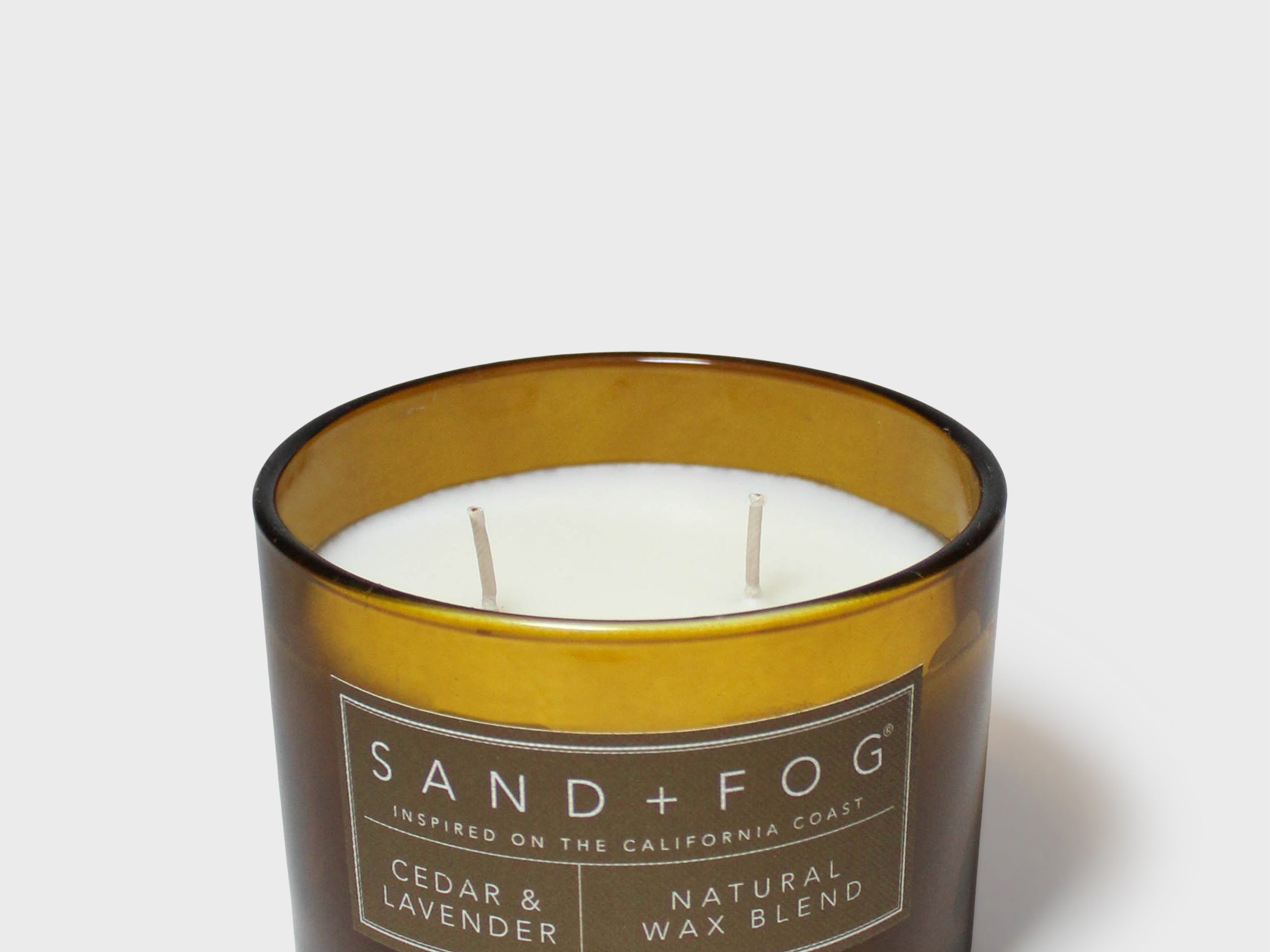Cedar-scented candle in dark glass jar with amber band and two wicks
