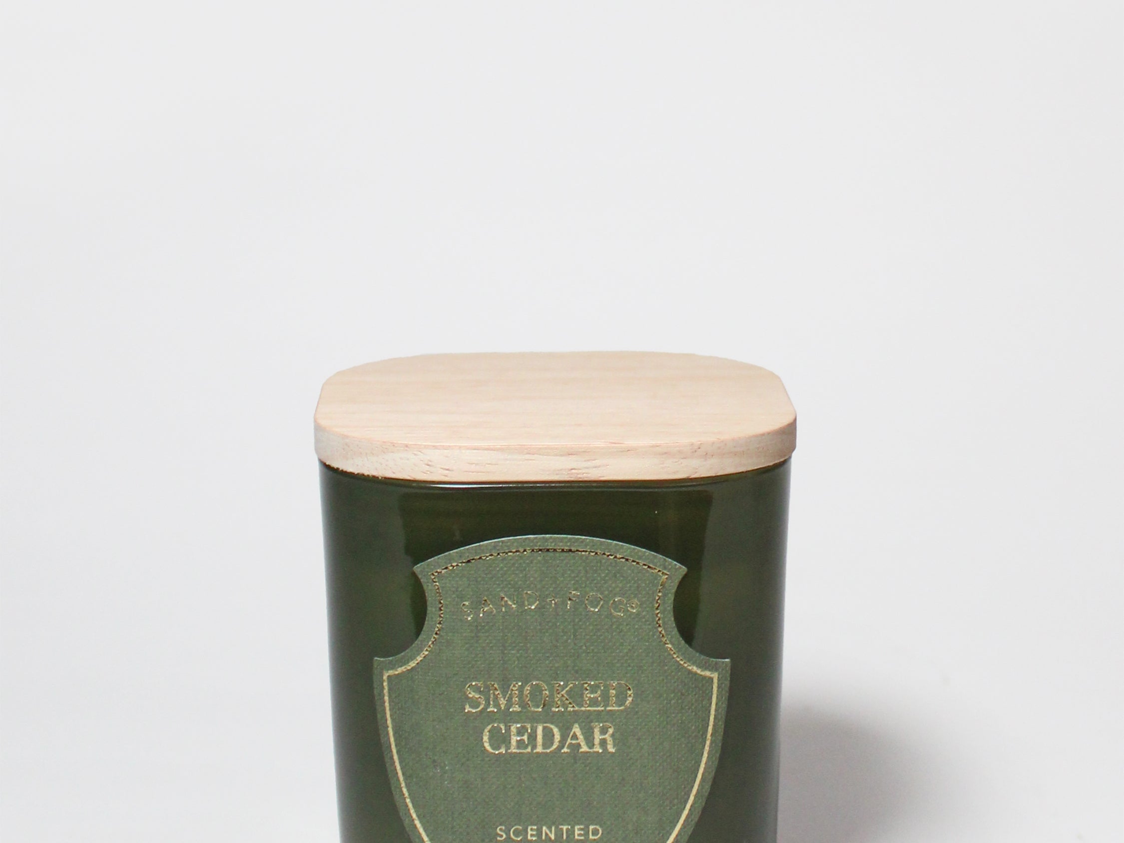 Smoked Cedar scented candle in a dark green glass vessel with a light wood lid.
