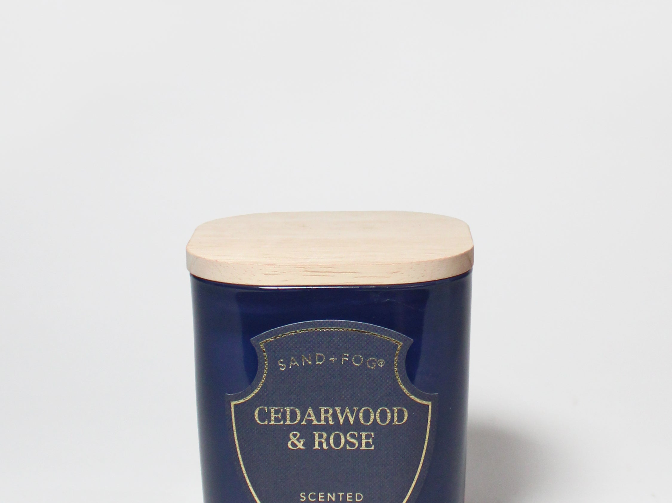 Cedarwood & Rose scented candle in a dark blue jar with a light wood lid