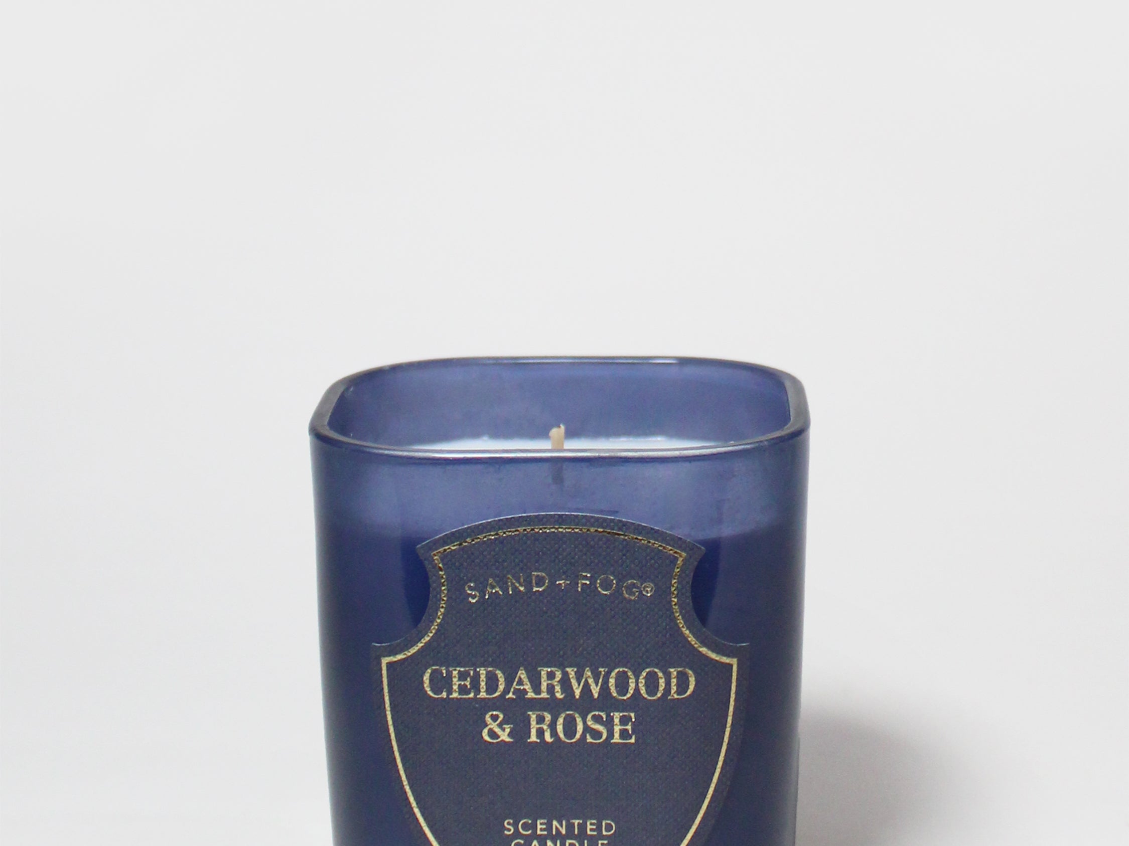 Cedarwood & Rose scented candle in a dark blue glass jar, shown without a lid