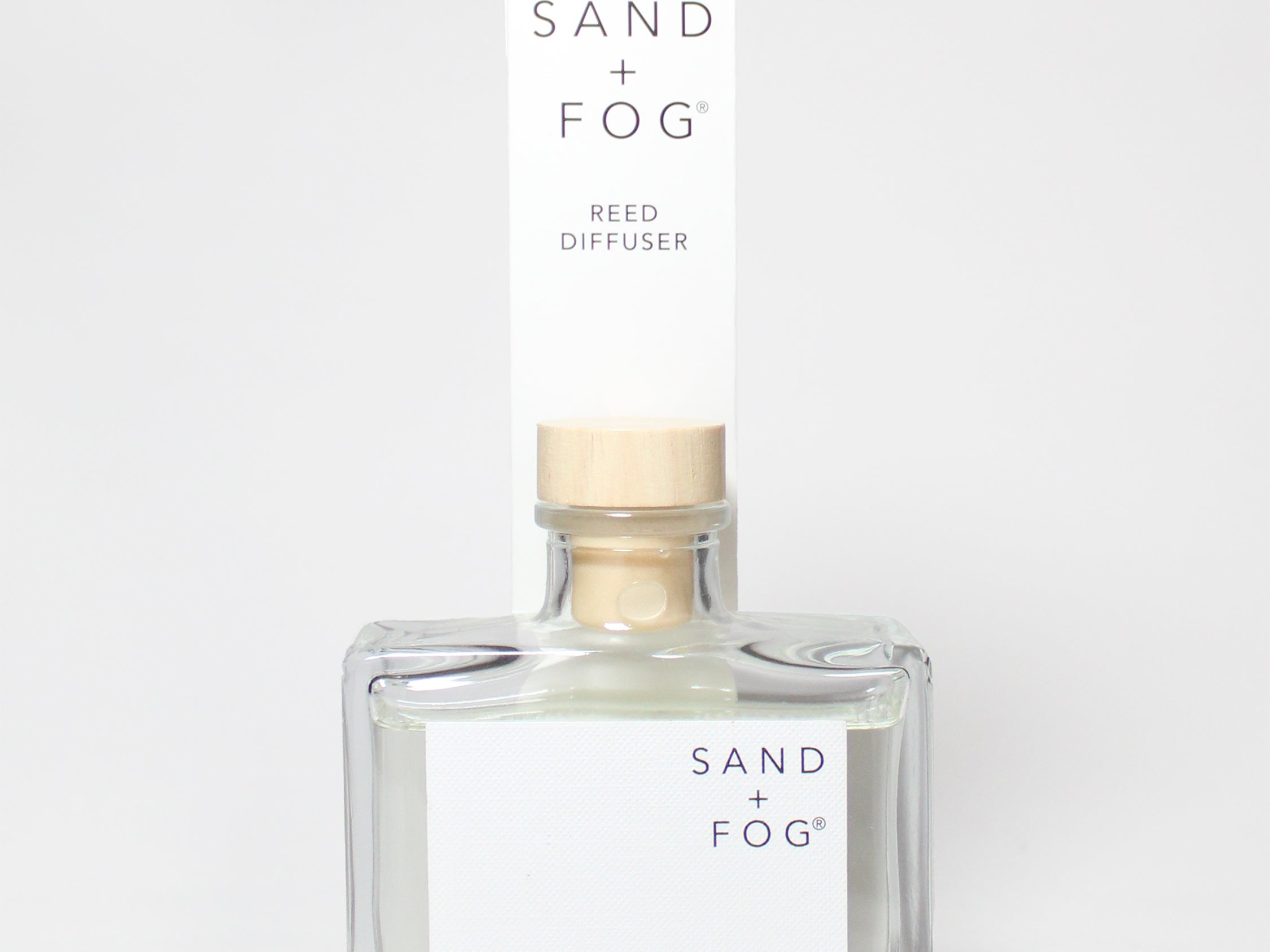 SAND + FOG Library reed diffuser in a clear glass bottle with a wooden cap.
