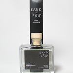 Vanilla Sandalwood reed diffuser in a clear square bottle with a wood cap and black box.