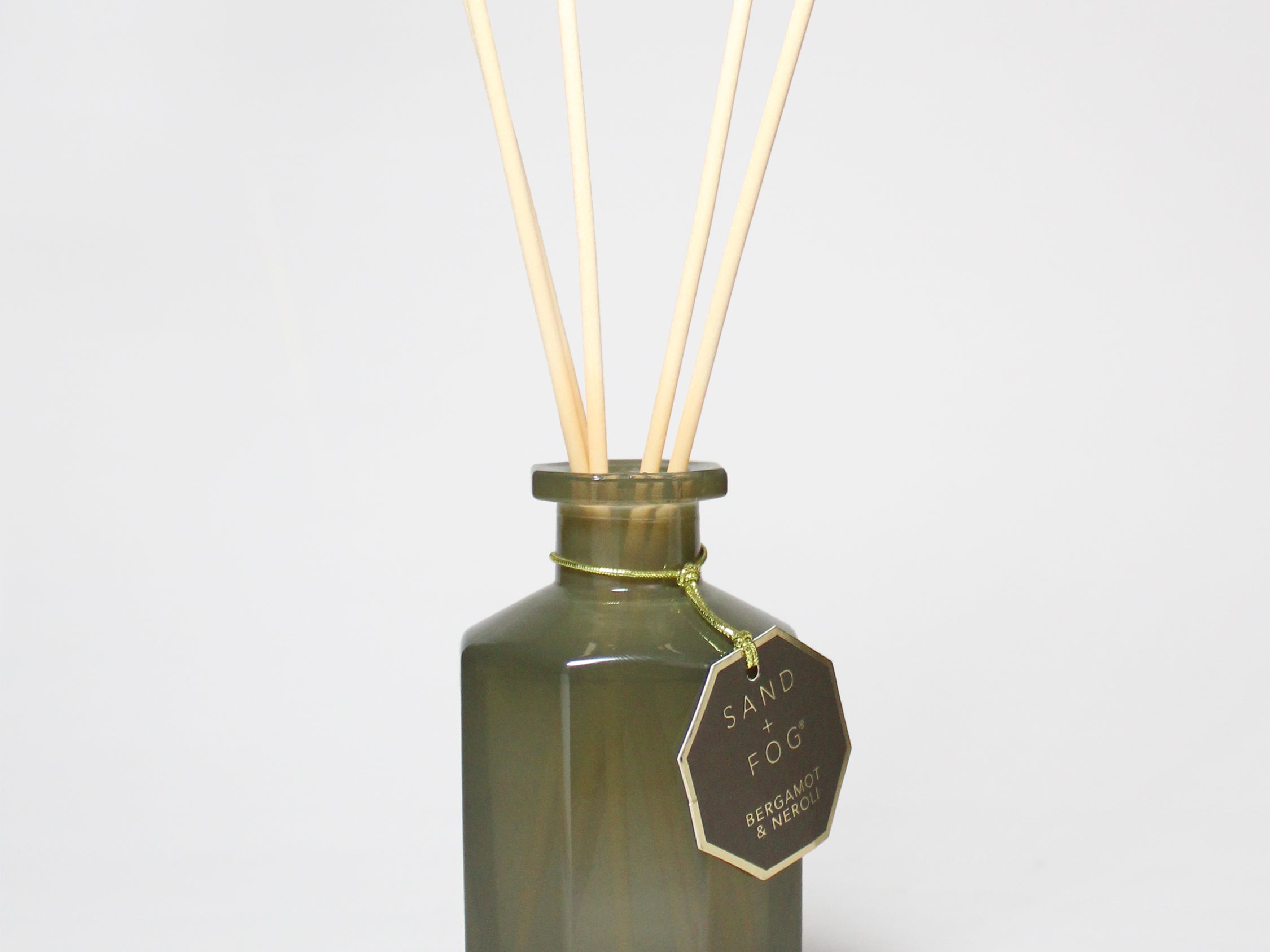 Bergamot and neroli reed diffuser in a dark green glass bottle with four reeds.