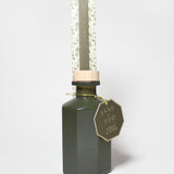 Forest & Ocean reed diffuser in a dark green glass bottle, topped with a clear protective tube
