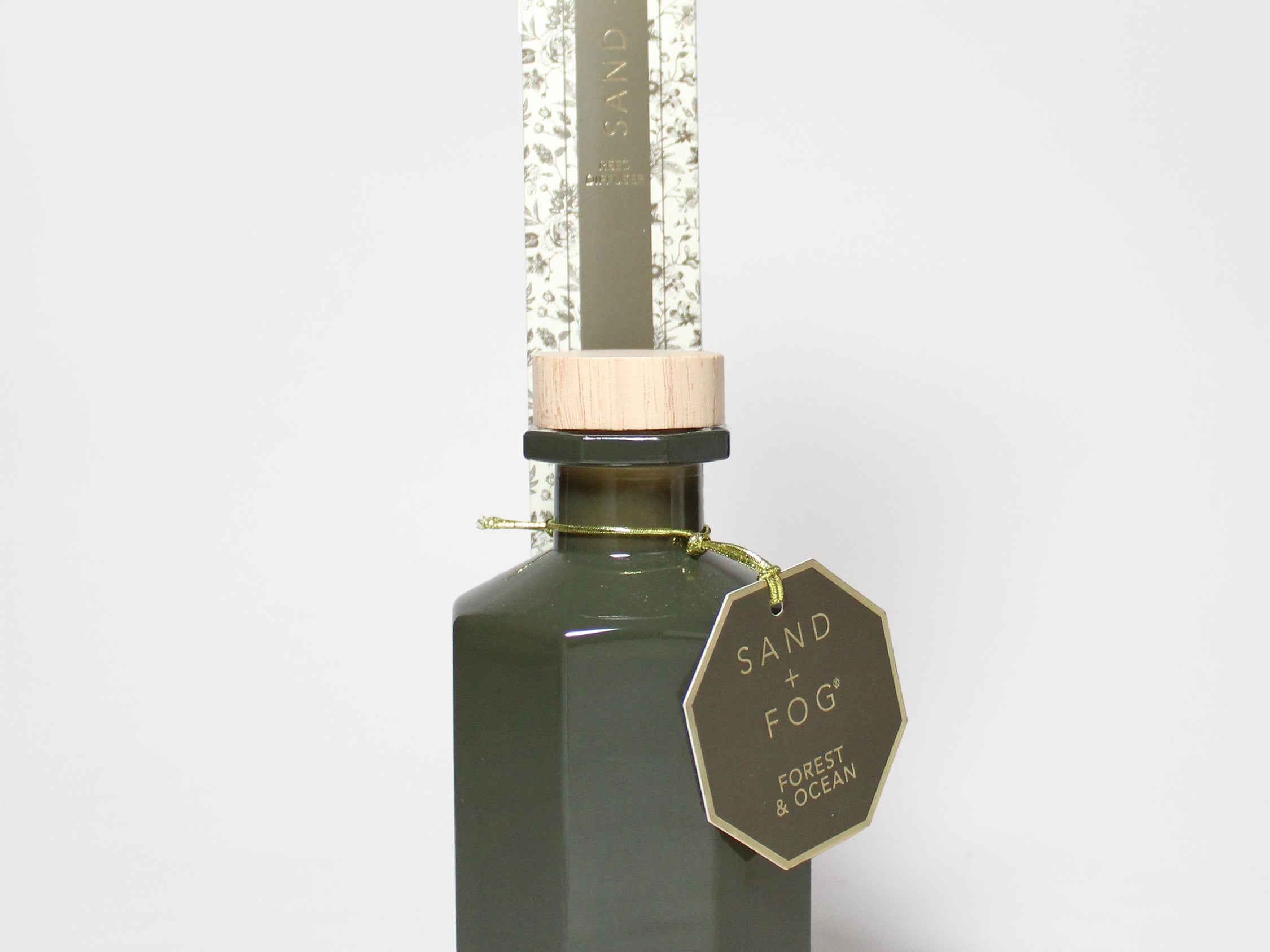 Forest & Ocean reed diffuser in a dark green glass bottle, topped with a clear protective tube