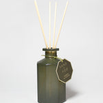 Forest & Ocean reed diffuser in a dark green glass bottle with four reeds and a hanging tag