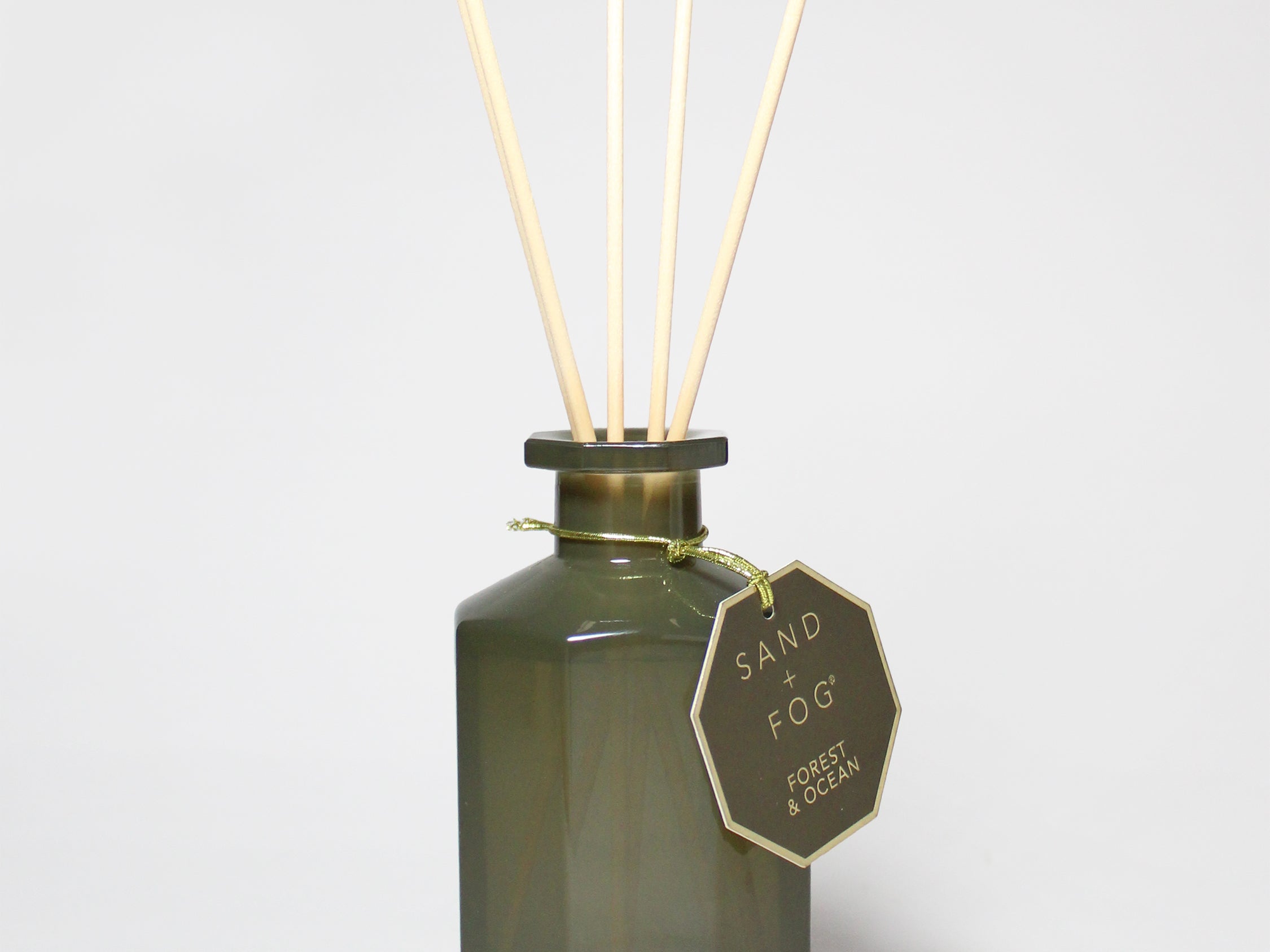 Forest & Ocean reed diffuser in a dark green glass bottle with four reeds and a hanging tag
