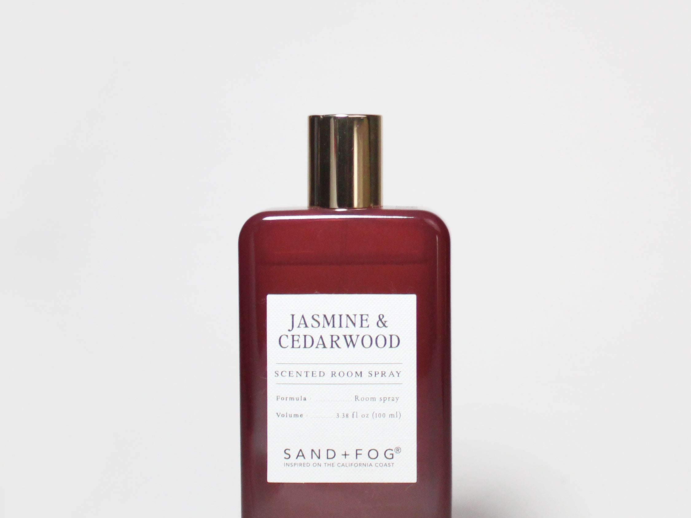 Maroon room spray bottle with gold cap and centered label